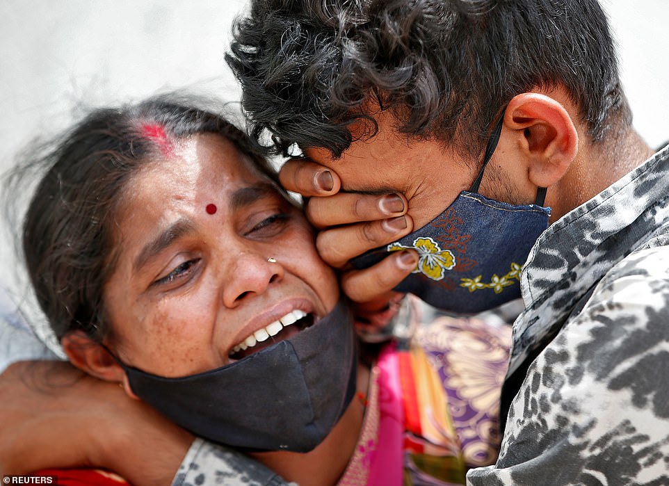 A woman mourns with her son after her husband died due to the coronavirus disease outside a mortuary of a COVID-19 hospital in Ahmedabad